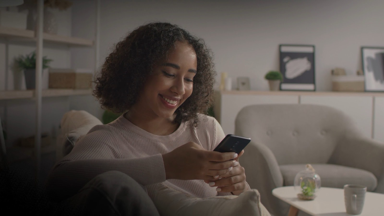 A still from a brand film: a woman smiling as she reads her phone